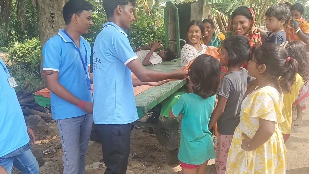 Volunteer handing clothes to a girl outside her home