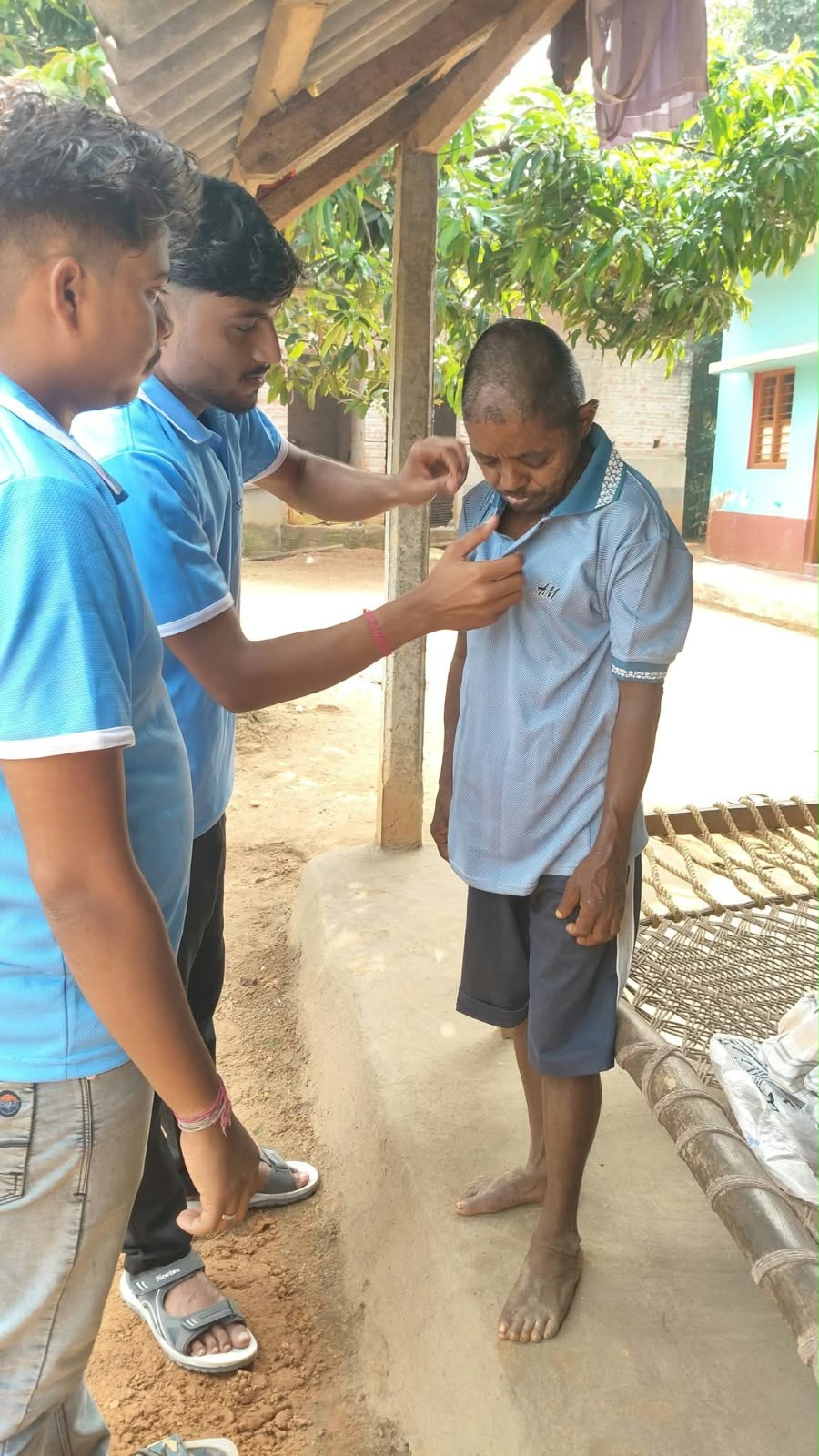 Volunteers helping a man put on a new shirt