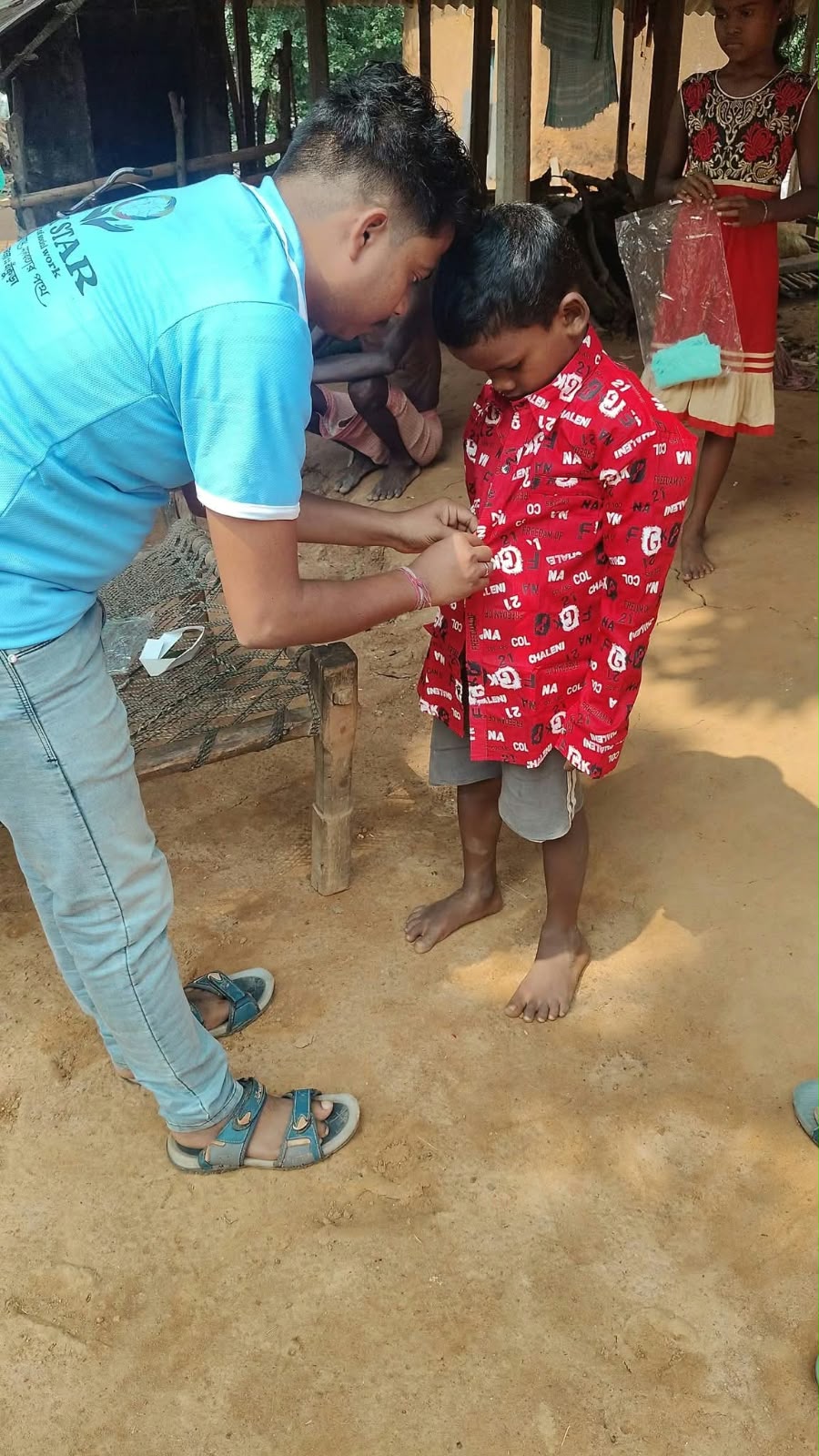 Volunteer helping a child wear a new shirt
